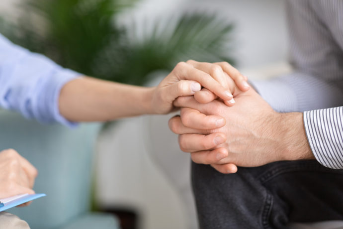 Woman holding man's hand in support gesture