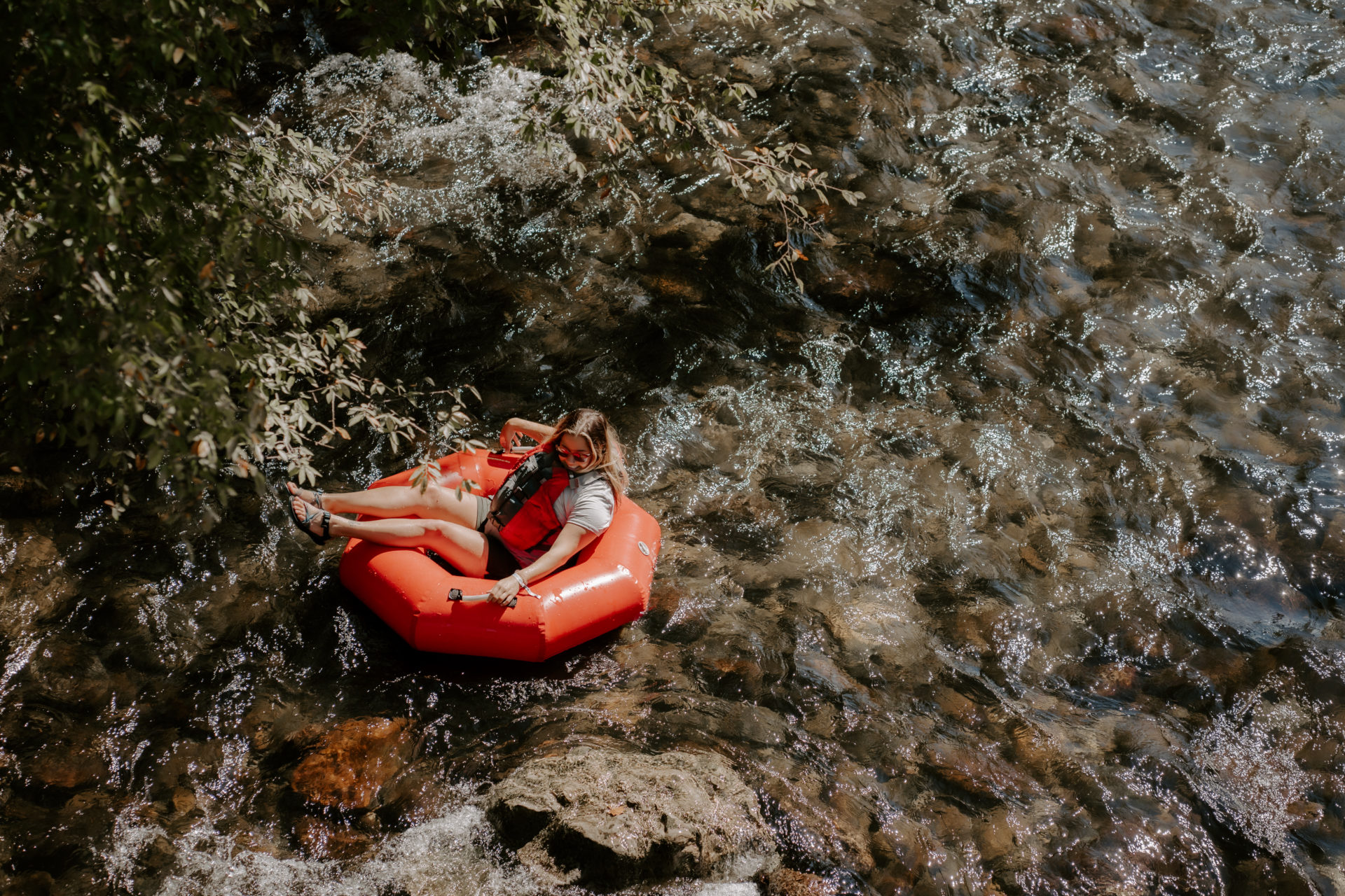 Lifestyle photography of a woman tubing in the Little River in Townsend, TN.