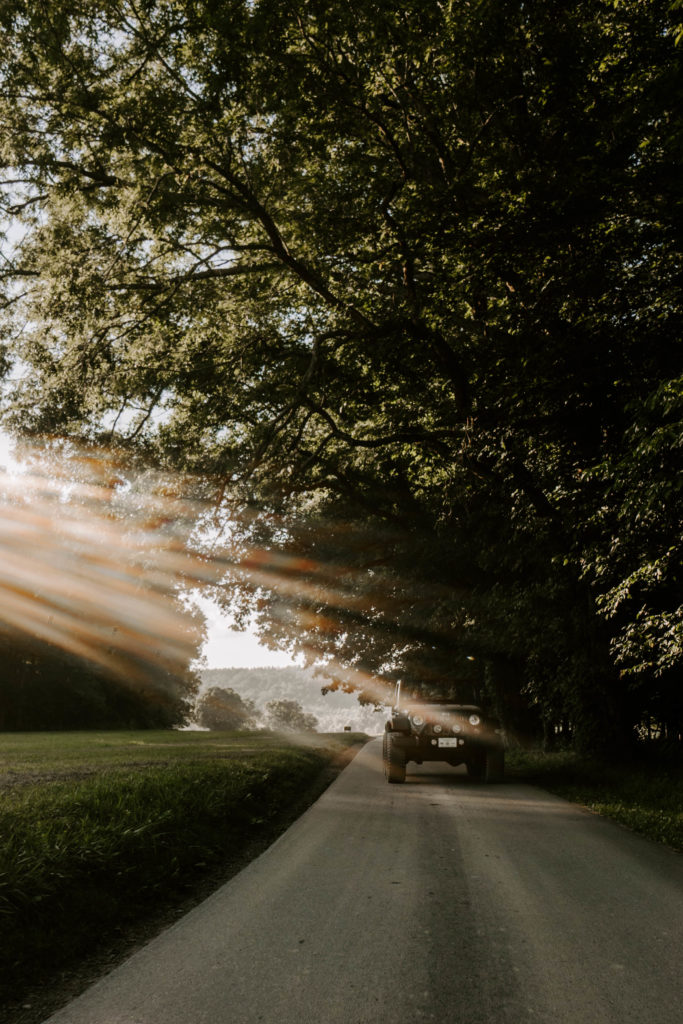 Lifestyle photography of a car driving down a road with trees above in Cades Cove in East TN.