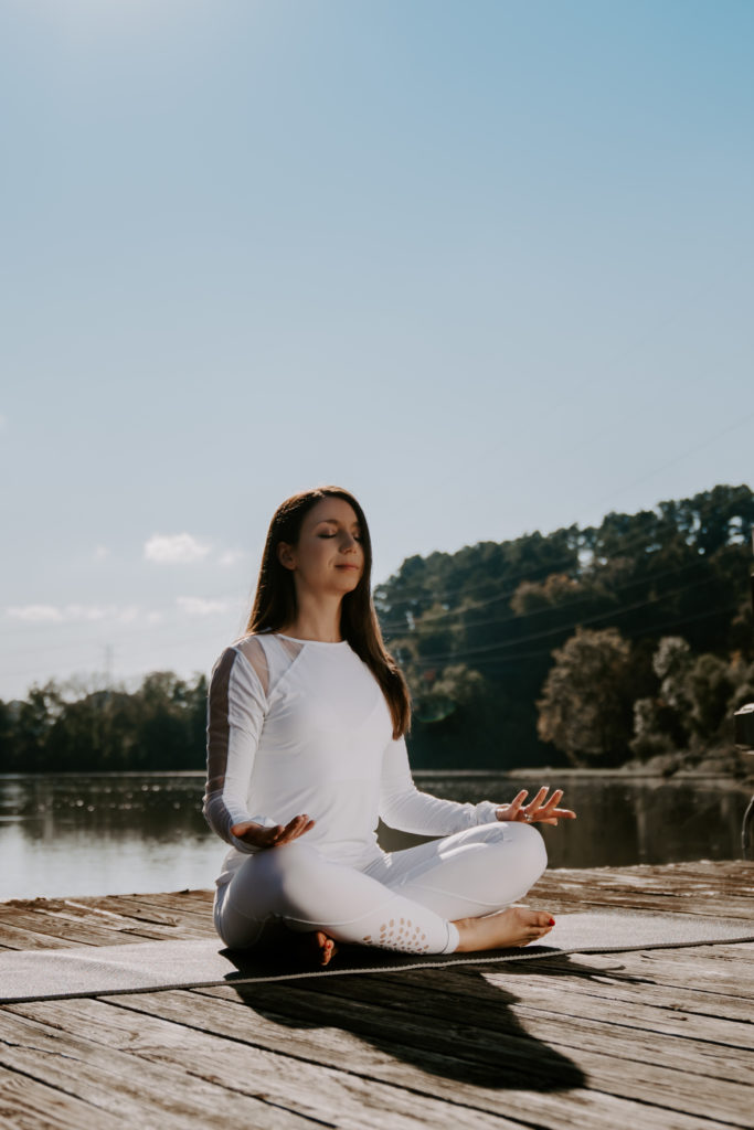 Commercial photography of a woman meditating on a pier.