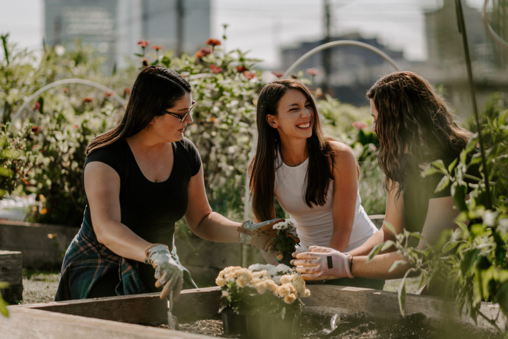 Commercial photography of three women gardening and laughing.
