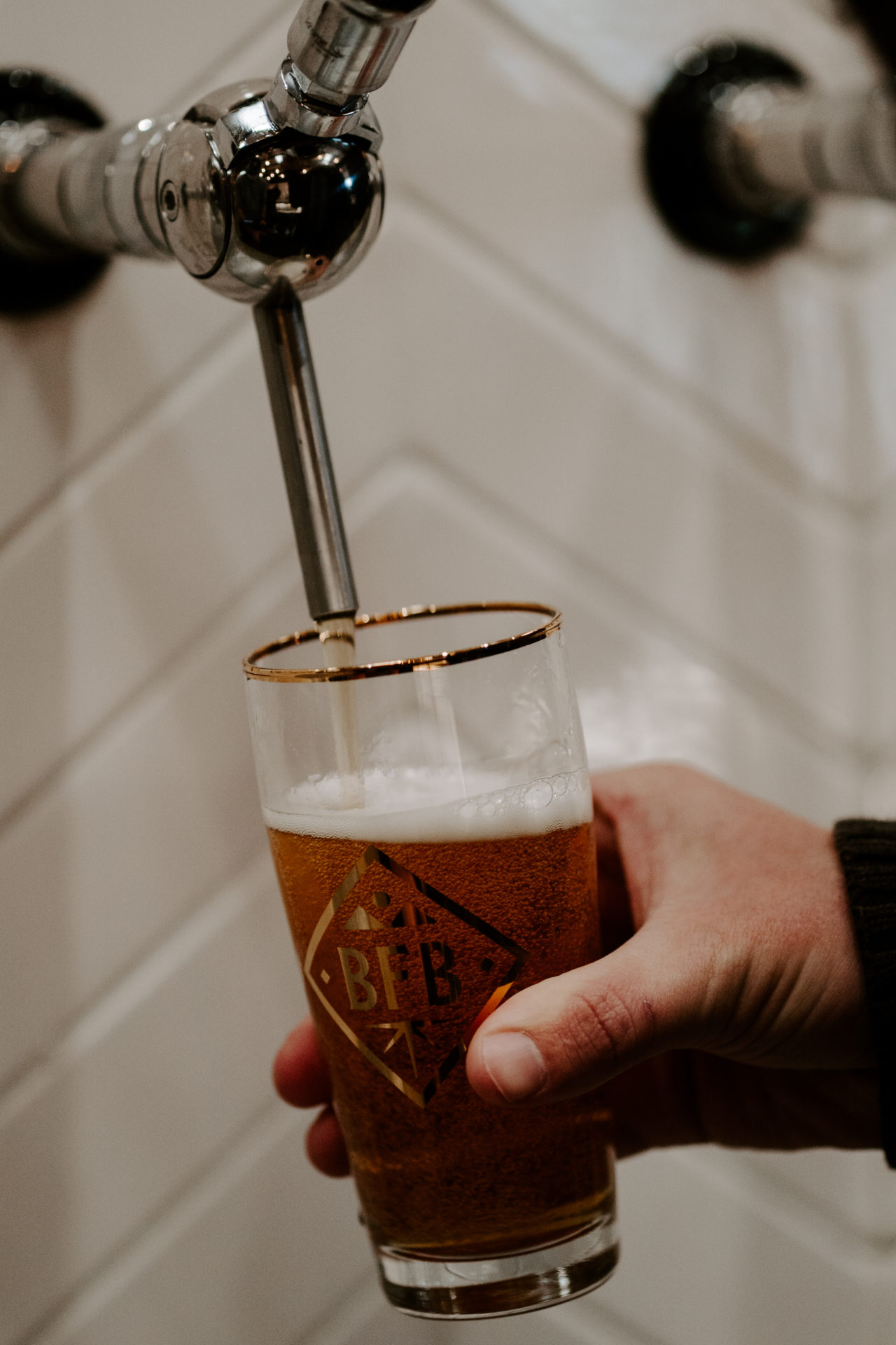 Product photography of a man holding a Blackberry Farm Brewery glass as it fills up with beer