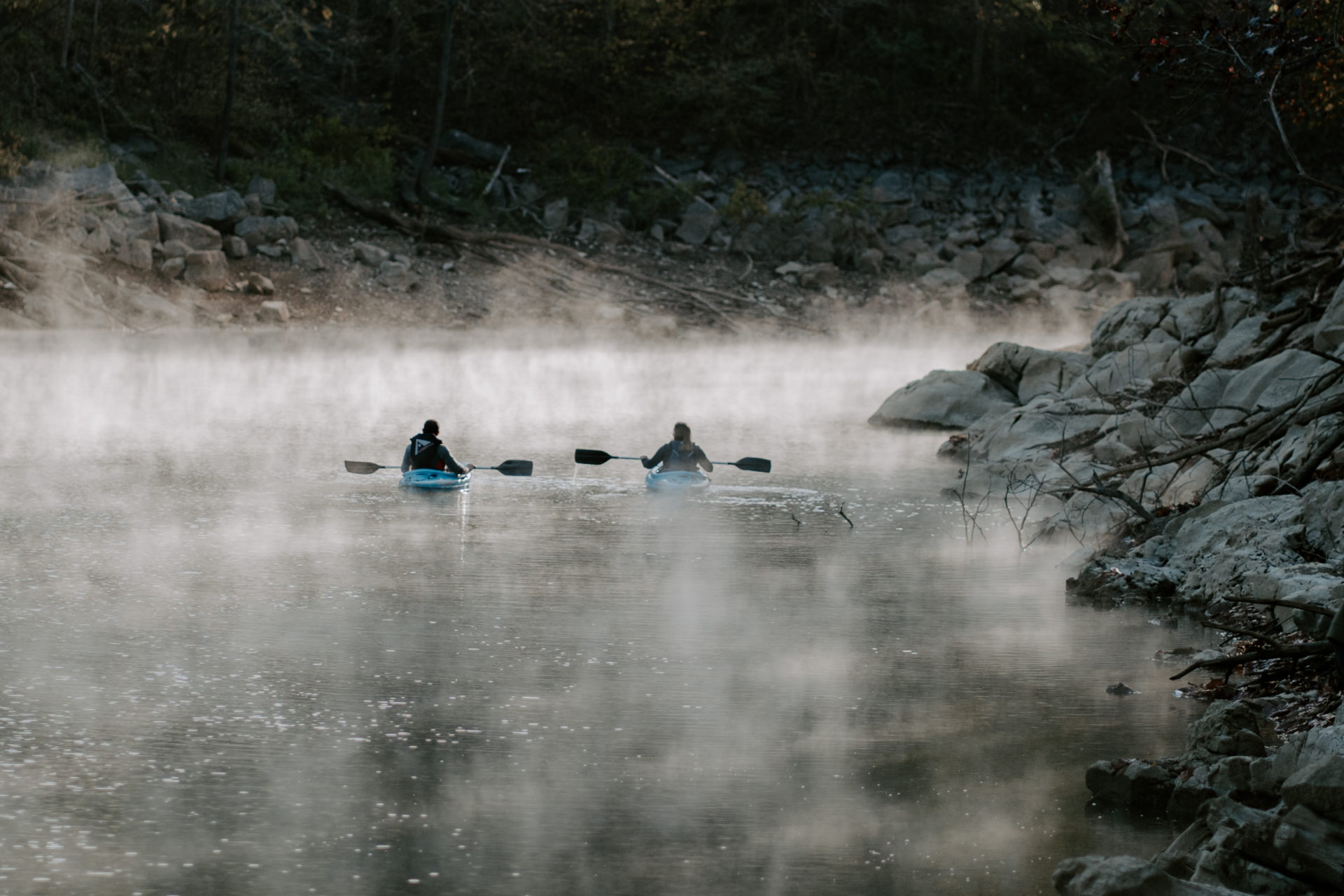 Lifestyle photography of two people kayaking on a foggy body of water in East TN.