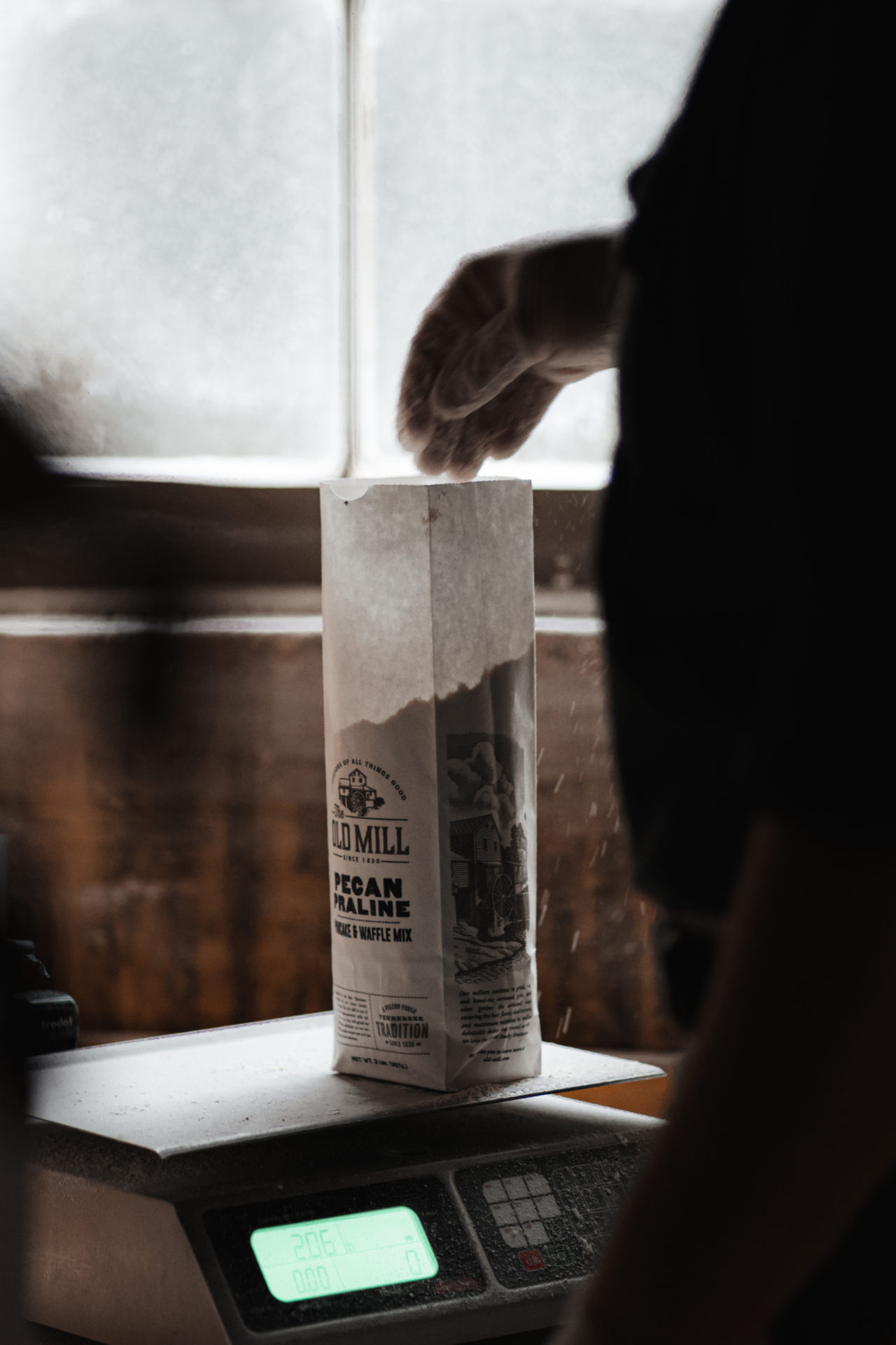 Product photography of a man reaching into a bag of flour with the Old Mill logo on it