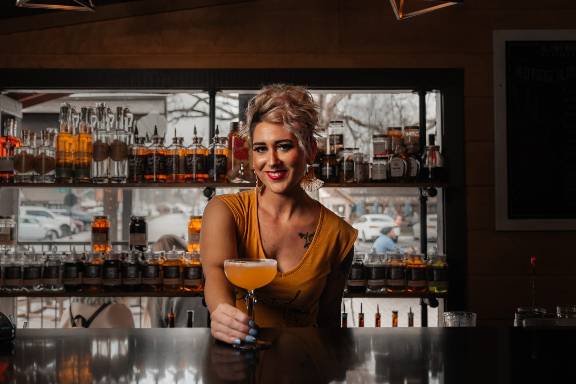 Commercial photography of a bartender at Old Forge Distillery handing a cocktail over the bar.