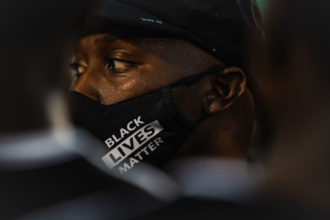 Coach John Netherland looking off camera wearing a face mask that says "Black Lives Matter"