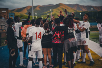 Austin East High School Men's soccer team circled up and holding their fists in the air