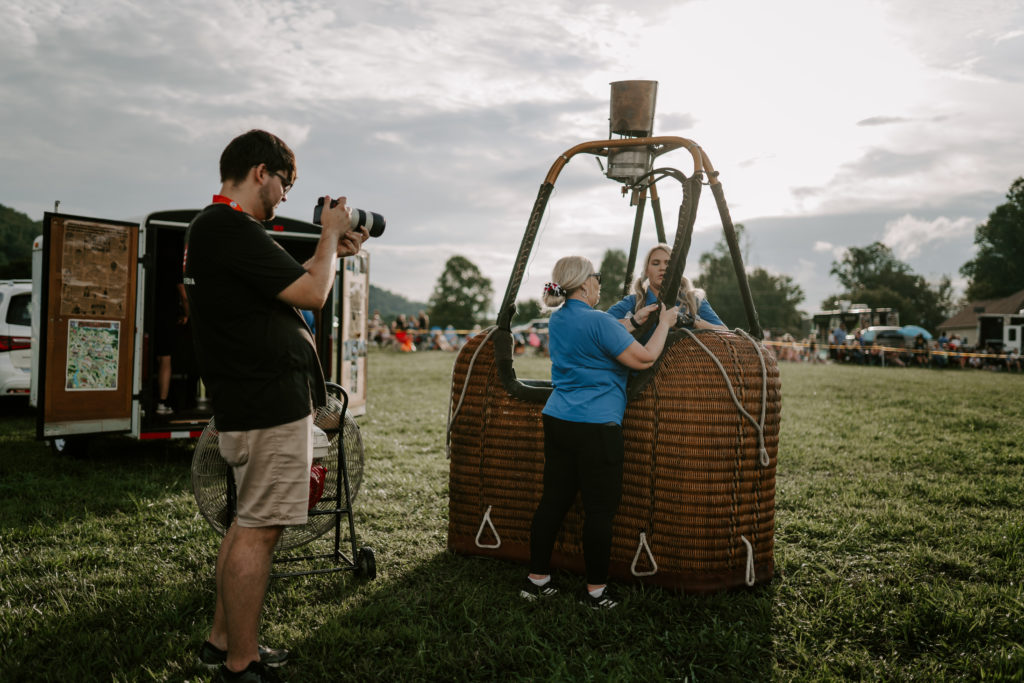 Eli Heaton pointing a camera at a woman setting up a hot air balloon