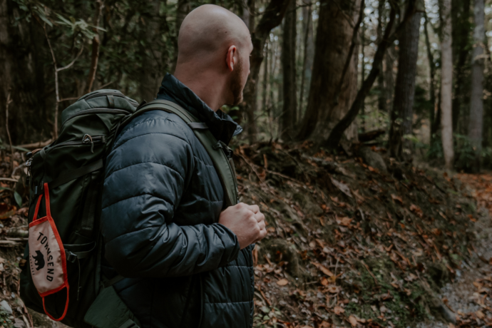 A man hiking in the Smoky Mountains with a Townsend mask on his backpack