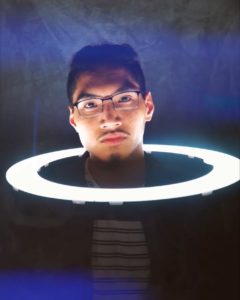 Neylan Bright with his head through a ring light that is turned on