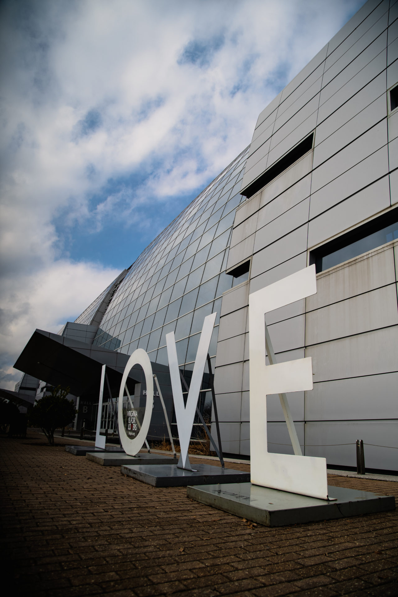 Event photography of a large 'LOVE' sign with a modern building in the background.