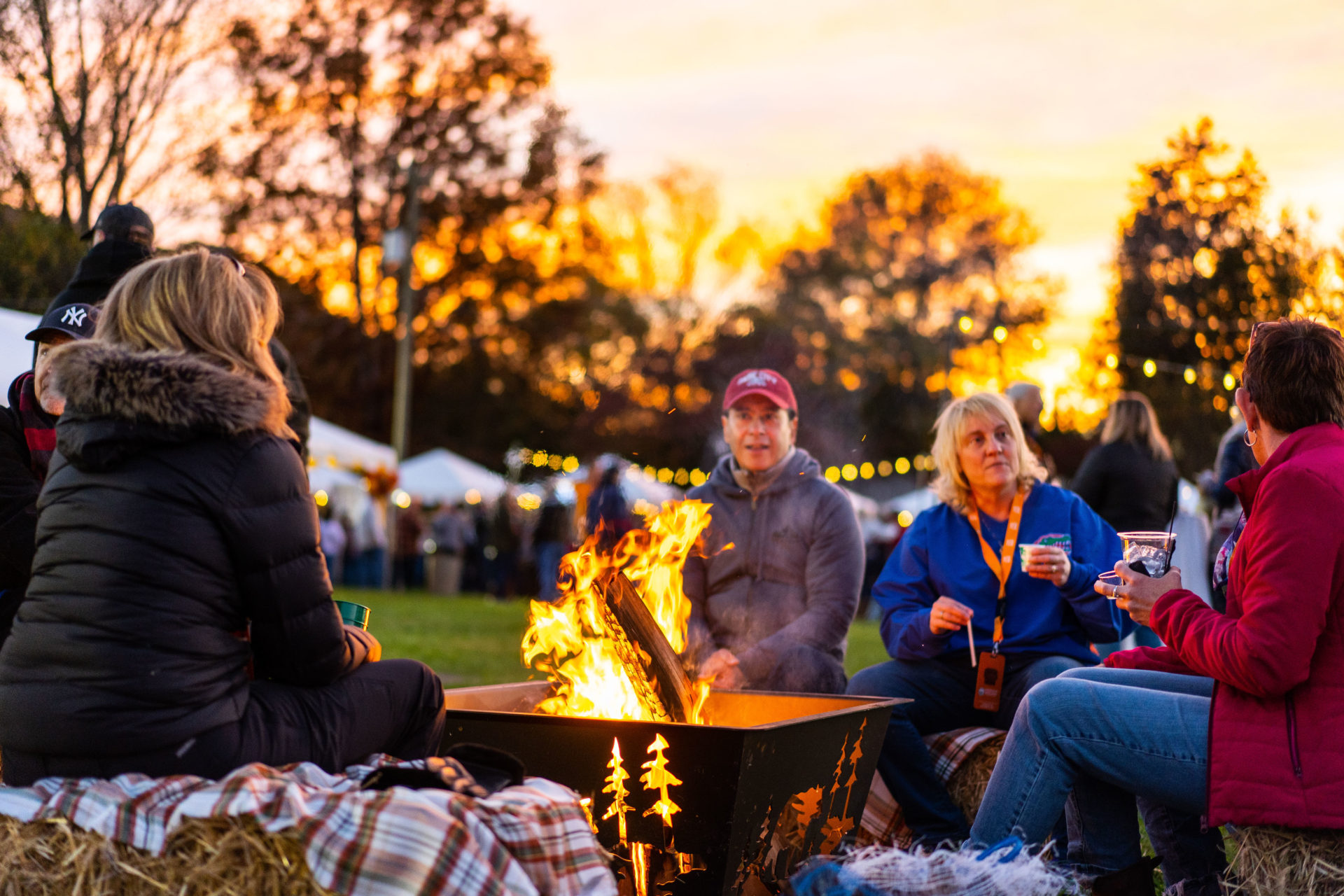 Event photography of a group of people seated around a bonfire and making conversation in Knoxville, TN.