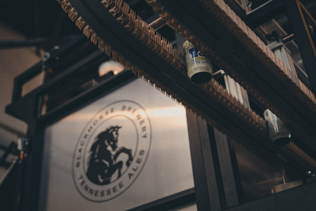 Commercial photography of a beer conveyor with the Blackhorse Brewery logo in the background in Knoxville, TN.