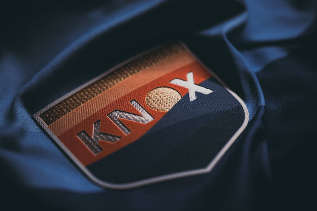 Close-up product photography of OneKnox logo on fabric shirt.