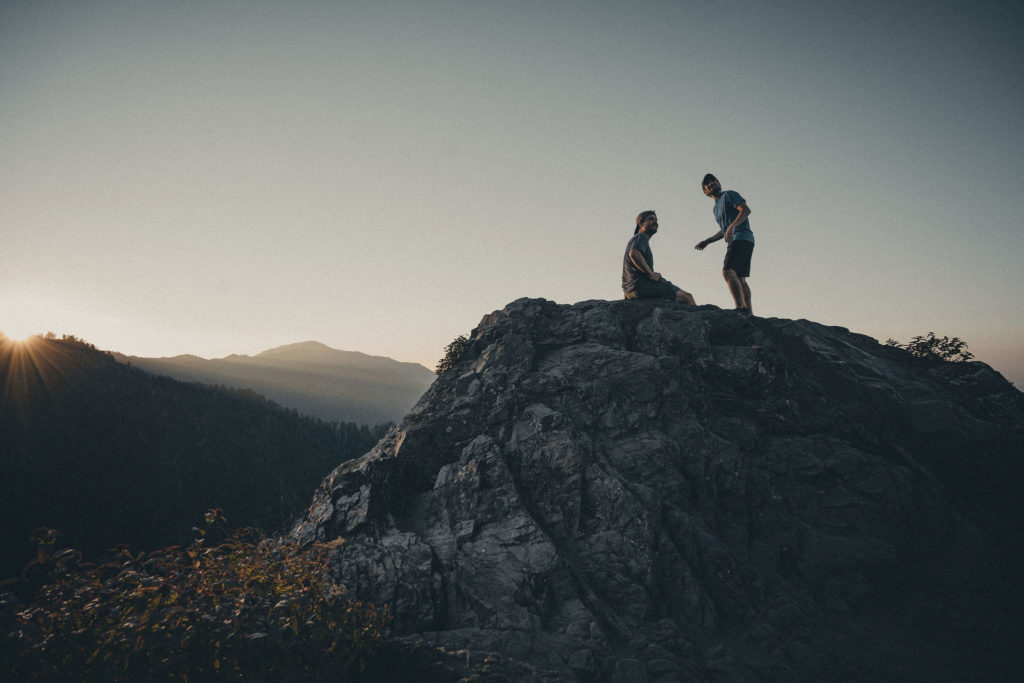 Lifestyle photography of two men on a hike standing at the top of an East Tennessee mountain as the sun rises.