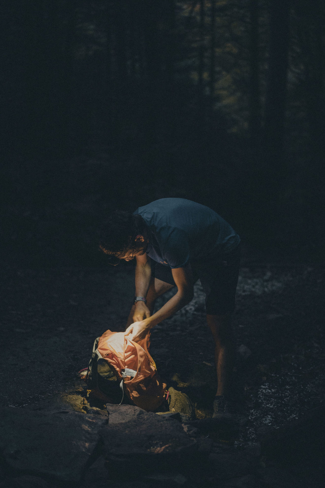 Lifestyle photography of a man hiking and searching his backpack with a flashlight in a forest in East Tennessee.