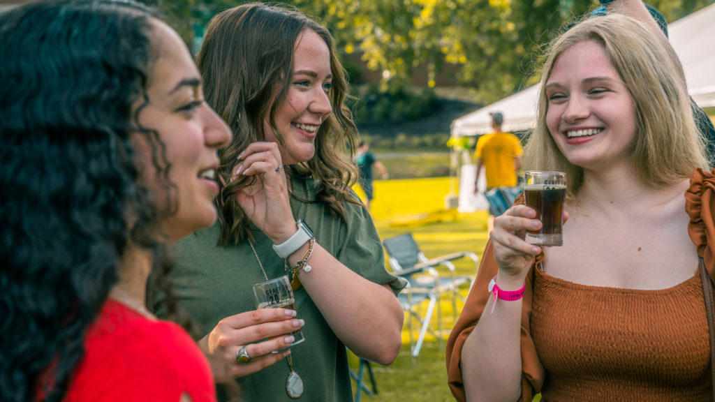 Event photography of three women smiling and drinking beer at a festival in Maryville, TN.