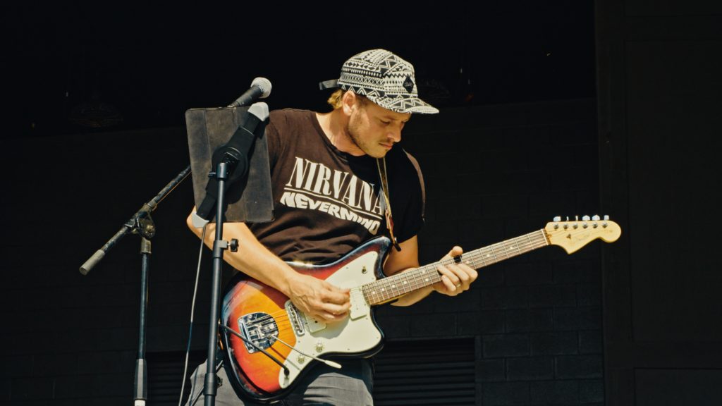 Event photography of a man in a black shirt playing guitar.