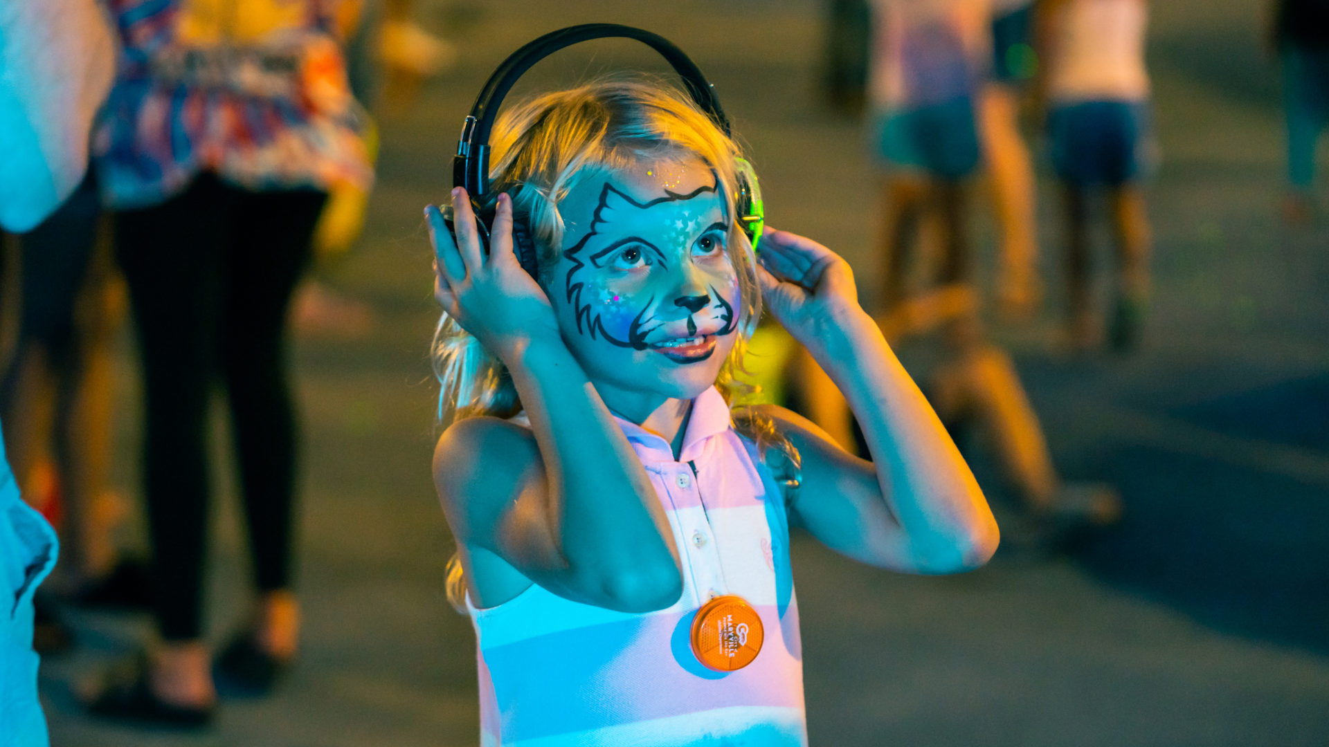 Event photography of a little girl with her face painted holding her headphones at a silent disco in Maryville, TN.