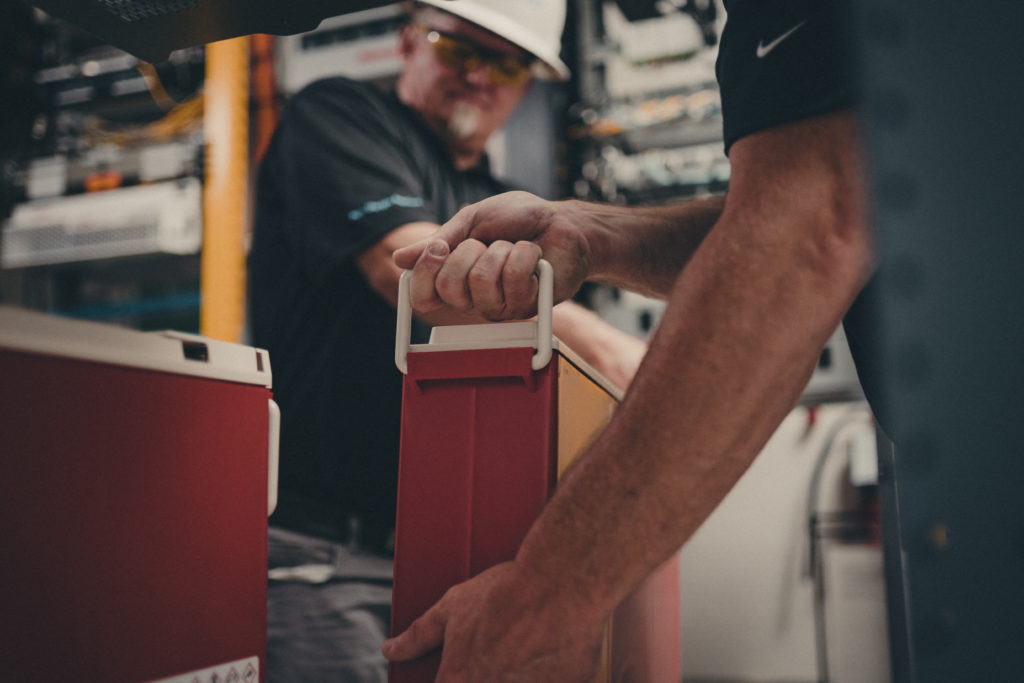 Close-up commercial photography of two employees moving power supplies.