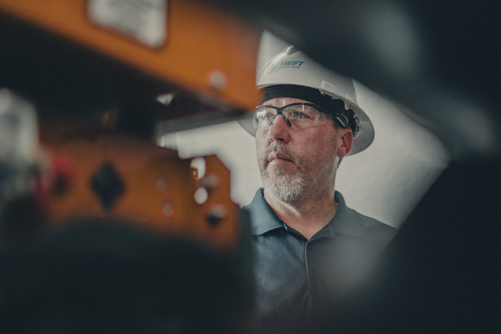Close-up commercial photography of the face of a Swift Industrial Power employee wearing a helmet.