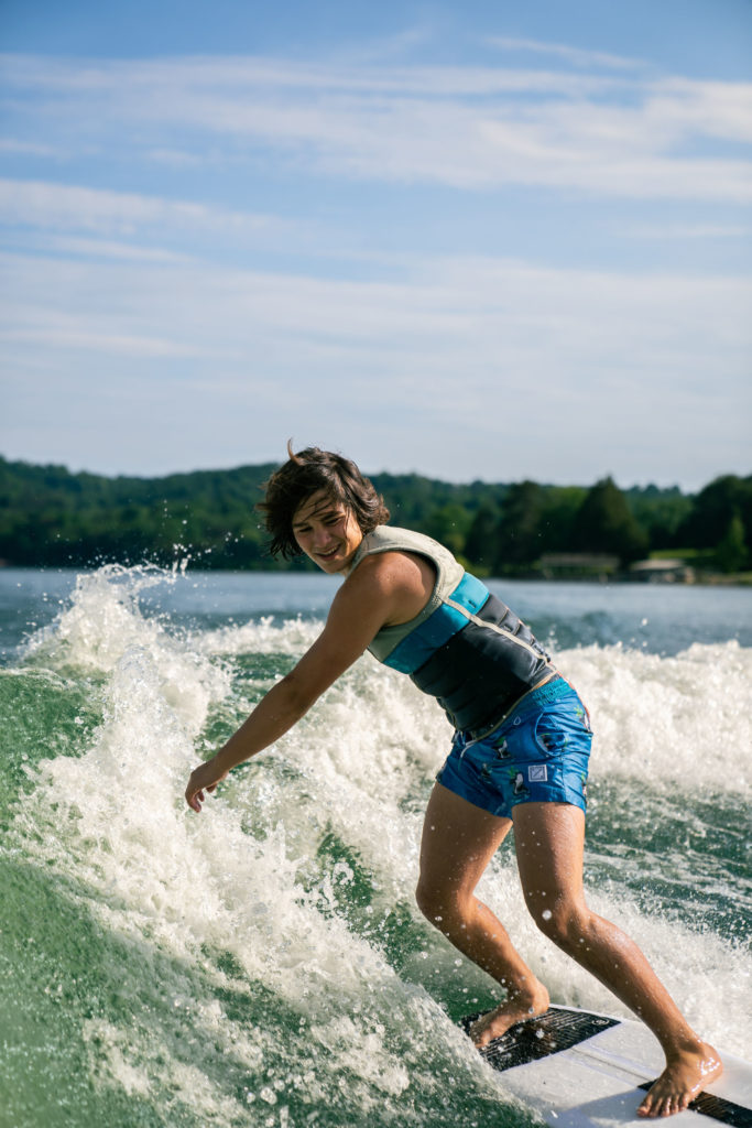 Lifestyle photography of a teen boy smiling as he wakeboards on a lake in East Tennessee.