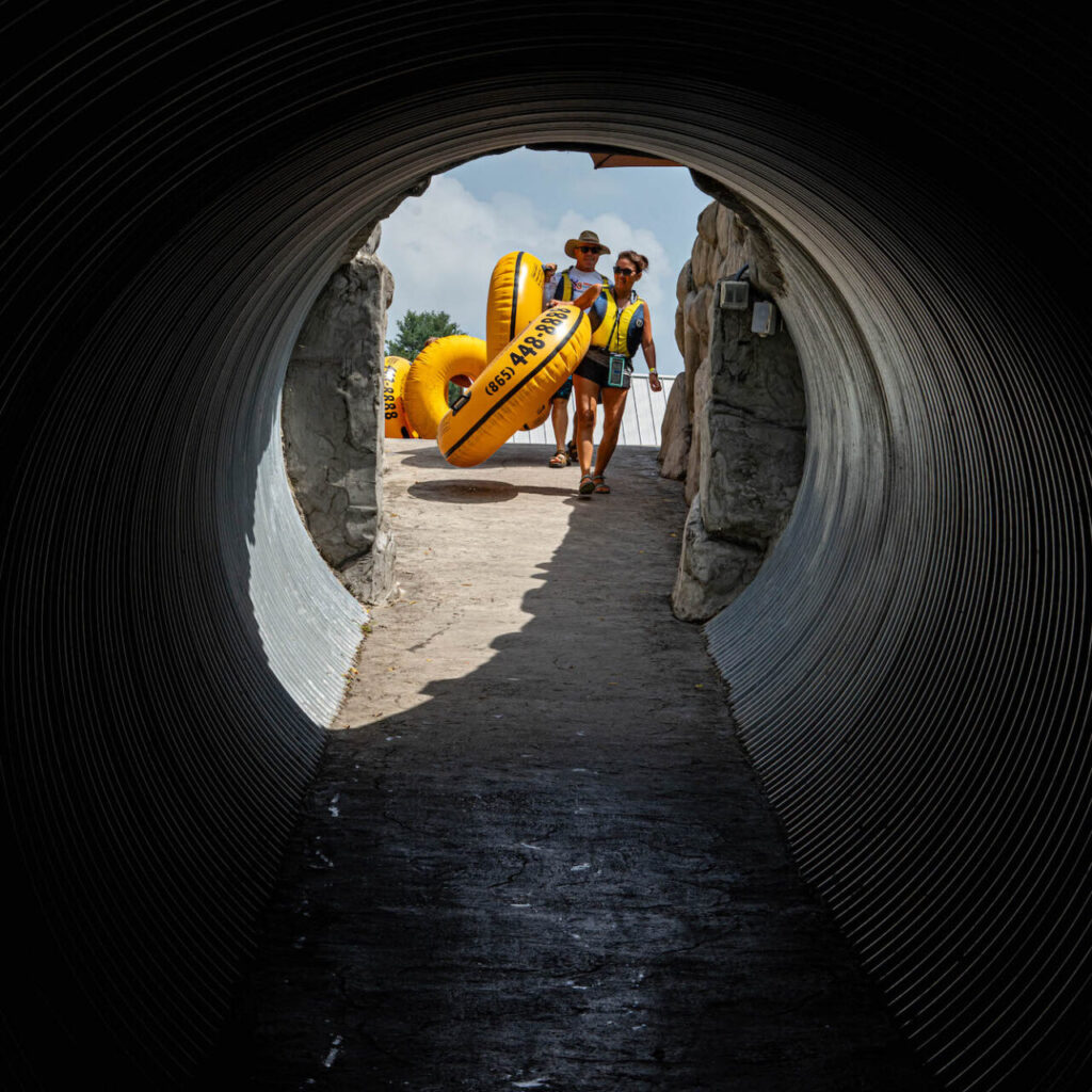 Looking down a tunnel at River Rat tubers holding their yellow tubes