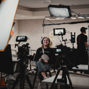 Mackenzie Ostrom sitting in a chair with an interview camera set up around her.