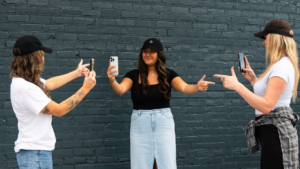 Three girls holding up their phone cameras to each other