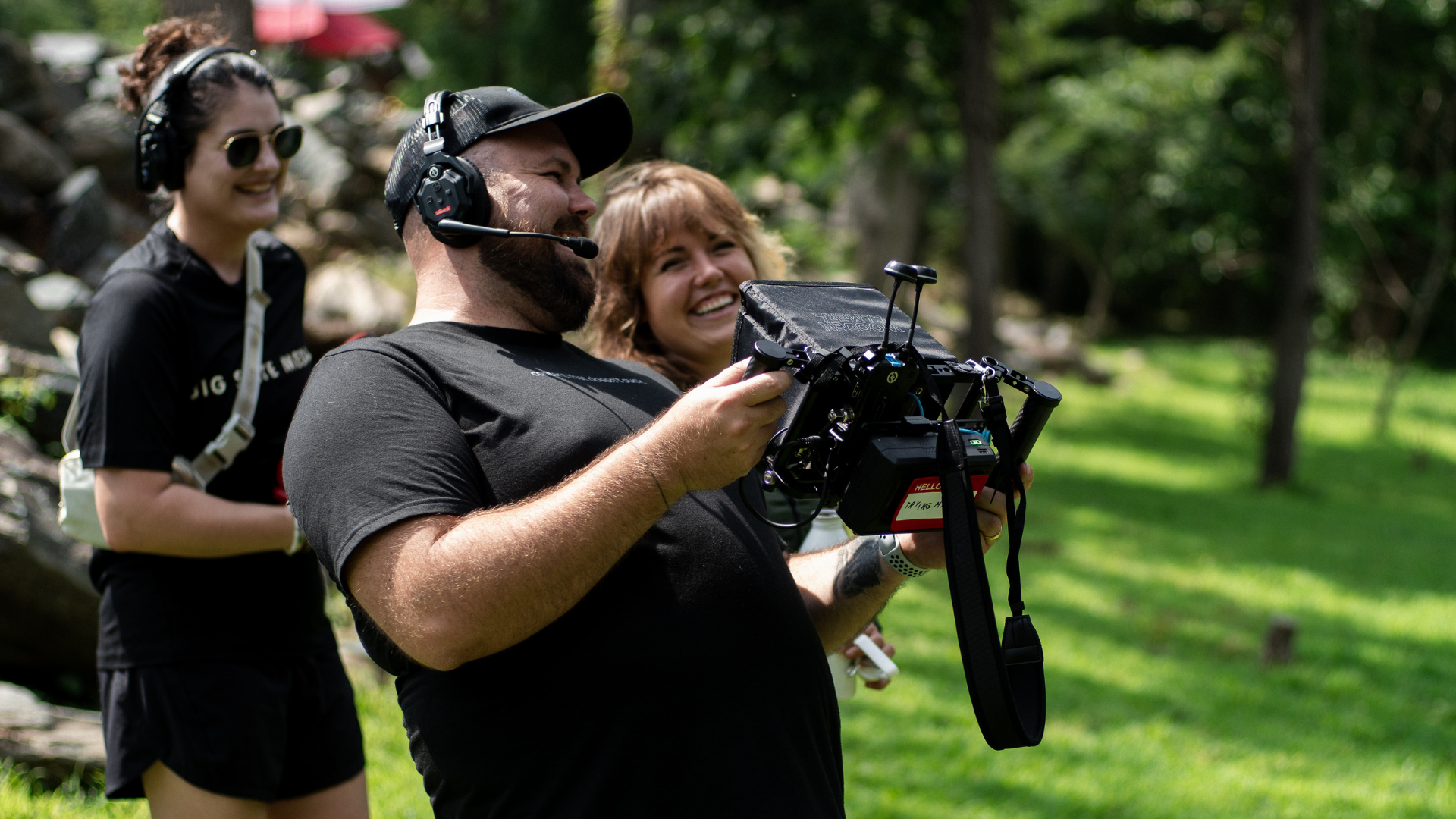 Jonathan Halley on a production set holing a director's monitor and laughing